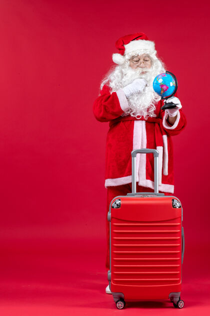 人圣诞老人的前视图 包里装着小地球仪 准备在红墙上旅行庆祝圣诞老人小