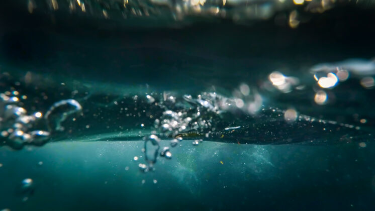 液体海水中漂浮在水面上的气泡的水下视图海水阳光度假