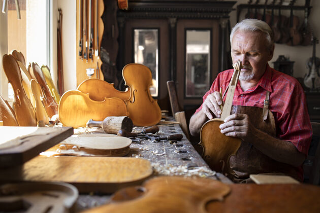 锤子高级木匠在他的木匠车间组装小提琴乐器的零件有才华仪器勤劳