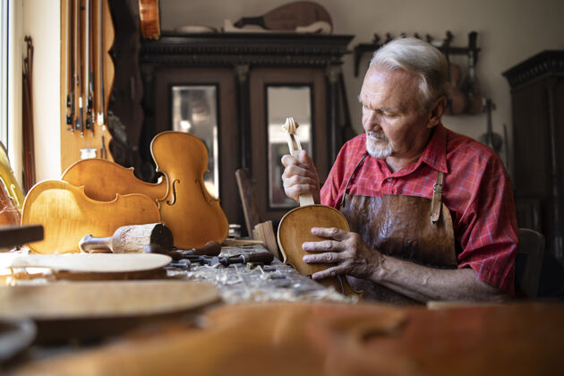 高级木匠在他的木匠车间组装小提琴乐器的零件锯末木制品制作