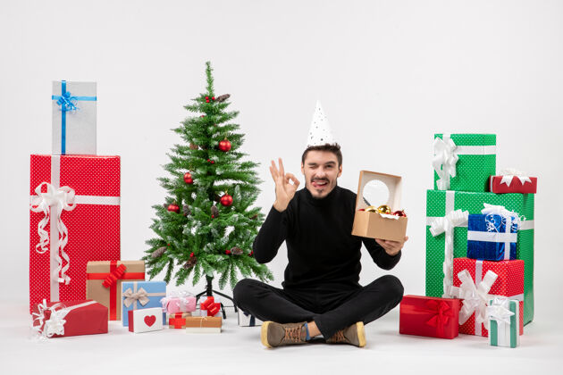 圣诞正面图：年轻人围坐在白色的墙上 手里拿着圣诞礼物礼物十二月人