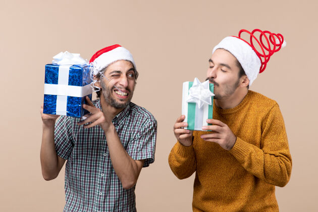 享受前视图两个幸福的家伙享受他们的圣诞礼物米色孤立的背景甜点男极乐