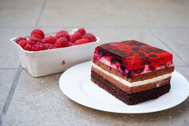 甜点特写镜头树莓在一个塑料容器旁边的树莓蛋糕块新鲜覆盆子糕点