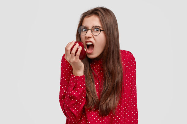 多汁愤怒饥饿的年轻女子恼怒地咬苹果的照片 由于坚持节食 心情不好 想吃东西护理保健饮食