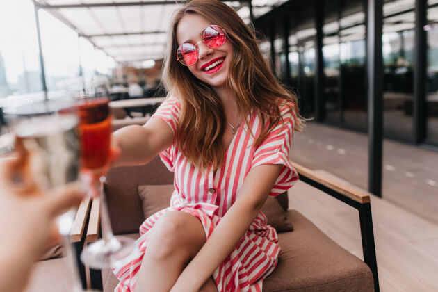 玻璃快乐的白色女孩穿着夏装在咖啡馆里度过时光性感的金发女郎戴着粉色眼镜的肖像 在温暖的日子里表达幸福优雅夏天享受