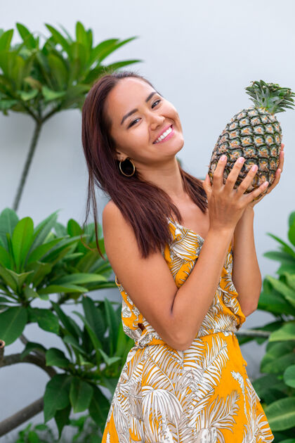 食物身着黄色夏装 手持菠萝的快乐亚洲微笑女人的画像欢乐健康水果