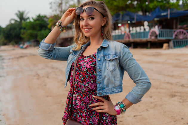乐趣穿着夏装度假的时髦女人戴着太阳镜在沙滩上散步活跃美丽女孩