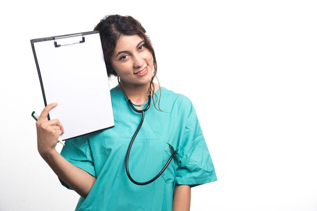 年轻女医生在白色背景上用钢笔和听诊器展示空剪贴板高质量照片成人剪贴板制服