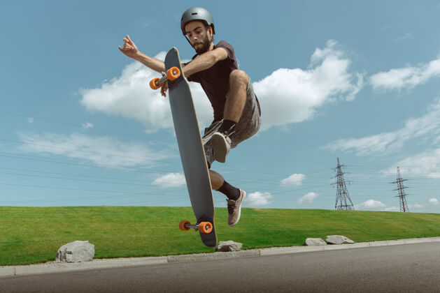 滑板在阳光明媚的日子里 在城市街道上玩滑板的人年轻人在草地附近骑马 玩长板休闲活动 运动 极限 爱好和运动的概念滑板游戏车轮