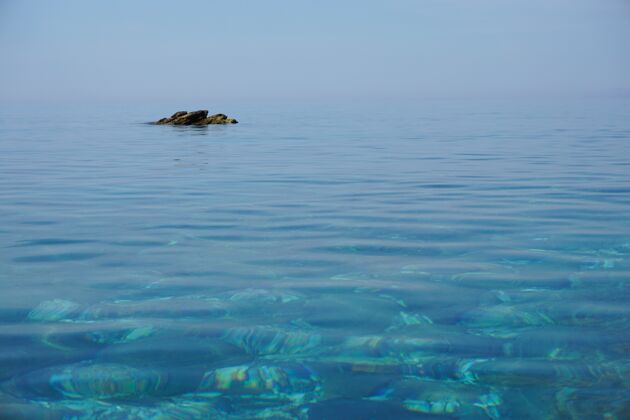 岩石在远离海岸的平静的海洋中 岩石形成的广阔镜头岸海白天