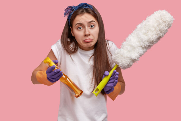 不满犹豫不快的女人拿着掸子和清洁液或喷雾剂 感到冷漠 不想整理房间个人持有清洗