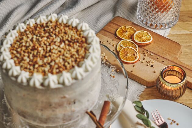 食物高角度拍摄的白色美味的圣诞蛋糕与坚果和柑橘玻璃盘子肉桂