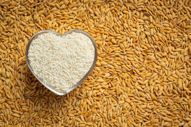 谷物白米饭放在心形碗里 地板上满是稻谷大米蛋白质纤维