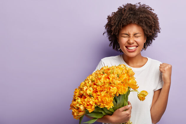 发型皮肤黝黑的凯旋女士肖像 收到情人送的漂亮花束 握紧拳头 欢笑笑非洲自由空间