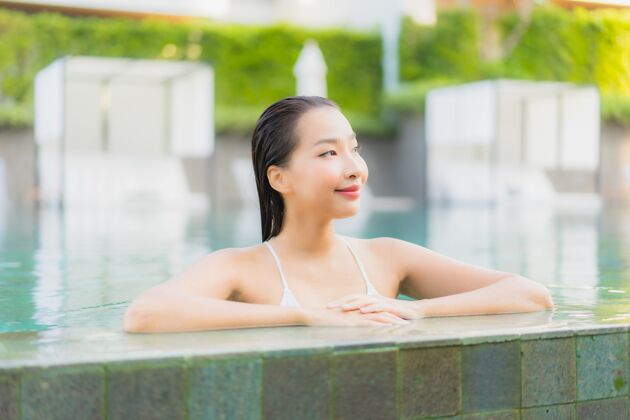 棕褐色肖像美丽的亚洲年轻女子放松微笑周围的室外游泳池在酒店度假村放松海滩游泳