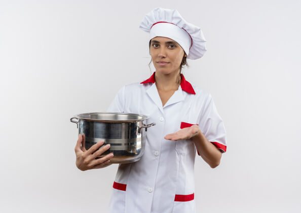 高兴高兴的年轻女厨师穿着厨师制服拿着和点手平底锅在隔离的白色墙壁上复制空间年轻制服女