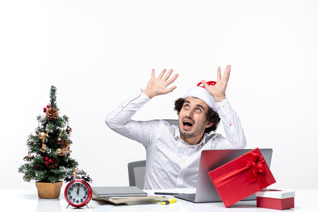 商人震惊不确定的年轻商人与有趣的圣诞老人帽子看在白色背景的办公室以上微笑电脑帽子