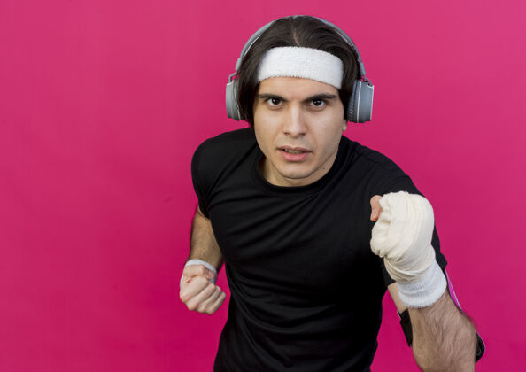运动型年轻的运动型男人穿着运动服和头带 戴着手机和智能手机臂带 紧张而自信地锻炼身体粉色智能手机运动装