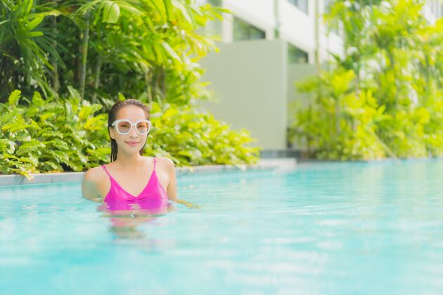 性感肖像美丽的亚洲年轻女子放松微笑周围的室外游泳池在酒店度假村水帽子热