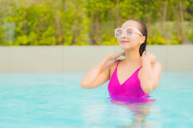 水肖像美丽的亚洲年轻女子放松微笑周围的室外游泳池在酒店度假村亚洲热放松