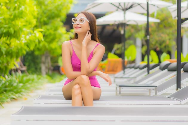 放松肖像美丽的亚洲年轻女子放松微笑周围的室外游泳池在酒店度假村身体女性游泳