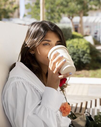 感染拿着花在户外喝咖啡的女人病毒雌性康乃馨