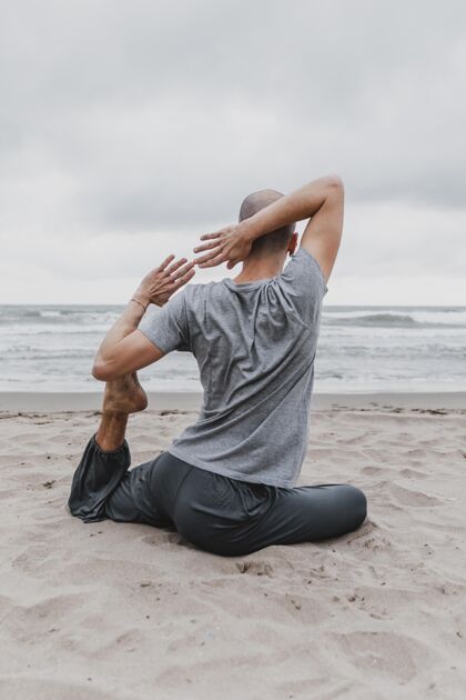训练海滩上练习瑜伽的男人的后视图专注瑜伽禅宗