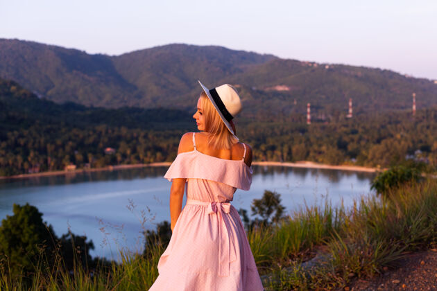 女人穿着夏装的年轻白种女人的浪漫肖像 在山上的公园里享受放松 美丽的热带海景 度假的女人 在泰国旅游日落时的快乐女人配饰漂亮衣服