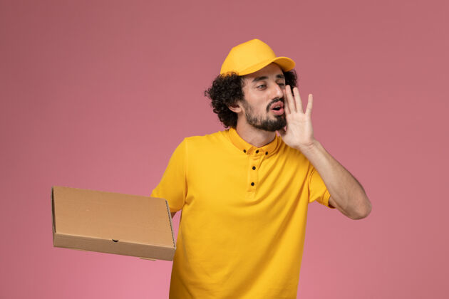 服务正面图身穿黄色制服的男快递员拿着食品快递箱在浅粉色的墙上大声呼喊送货工人成人