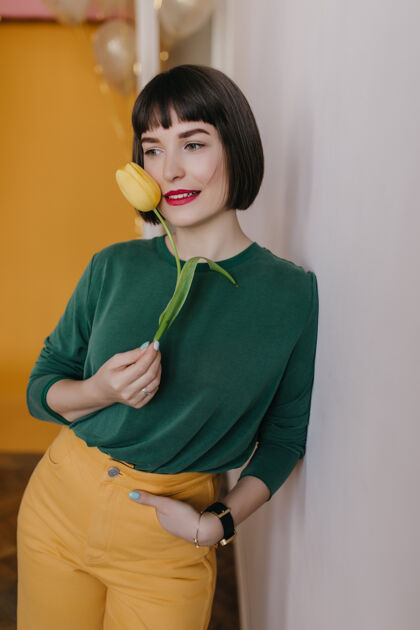 年轻穿着绿色毛衣的放松的女模特与郁金香合影室内浪漫的高加索女孩微笑着捧着花黄色花乐趣植物