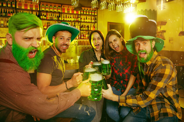 成人圣帕特里克节聚会快乐的朋友们正在庆祝和喝绿色啤酒节日酒吧情绪