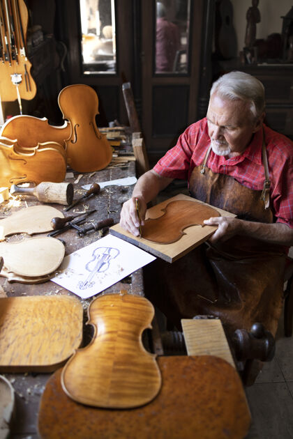 艺术性资深木匠在他的老式木匠作坊里制作小提琴乐器真品素描木材