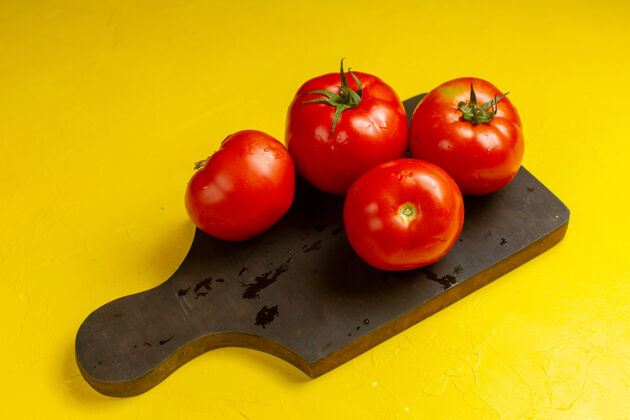 西红柿黄色表面上新鲜红色西红柿的正面图西红柿食品饮食