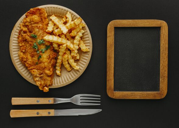 美食用黑板和餐具在盘子上的鱼和薯条的俯视图餐鱼油炸