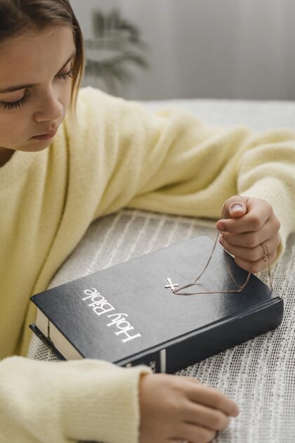 祈祷侧视图女孩祈祷与圣经和交叉项链垂直虔诚虔诚