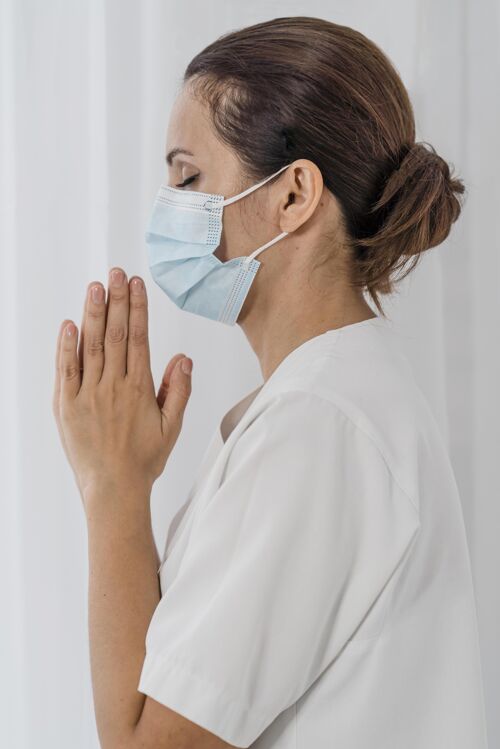 信仰护士戴着医用面罩祈祷的侧视图护士面具虔诚