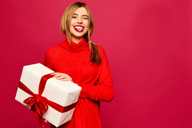传统微笑的女人拿着许多礼盒在红墙上摆姿势青少年享受白种人